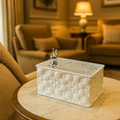 Decorative white box with silver emblem on a table in a luxurious room.