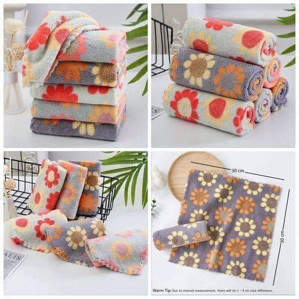 Stacks of floral patterned towels on a white surface with green leaves in the background.