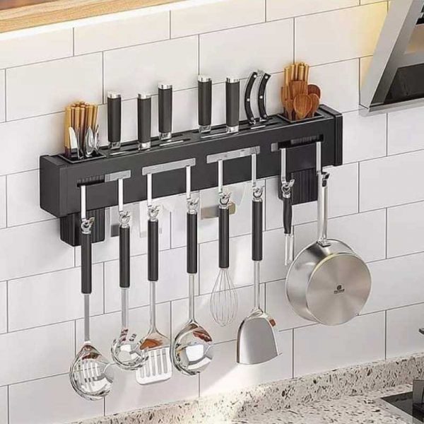 Wall-mounted kitchen utensil holder with various tools on a tiled wall.