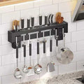 Kitchen utensil rack with various utensils hanging on a tiled wall.