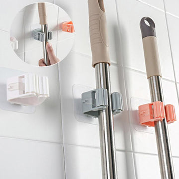 Mop and broom holders on a tiled wall with close-up of hand using holder.