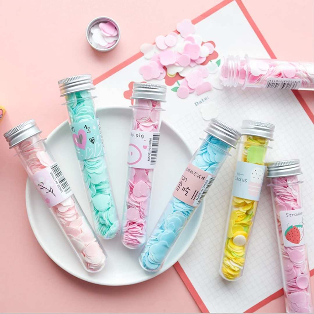 Colorful test tube-shaped containers with decorative labels on a pink background