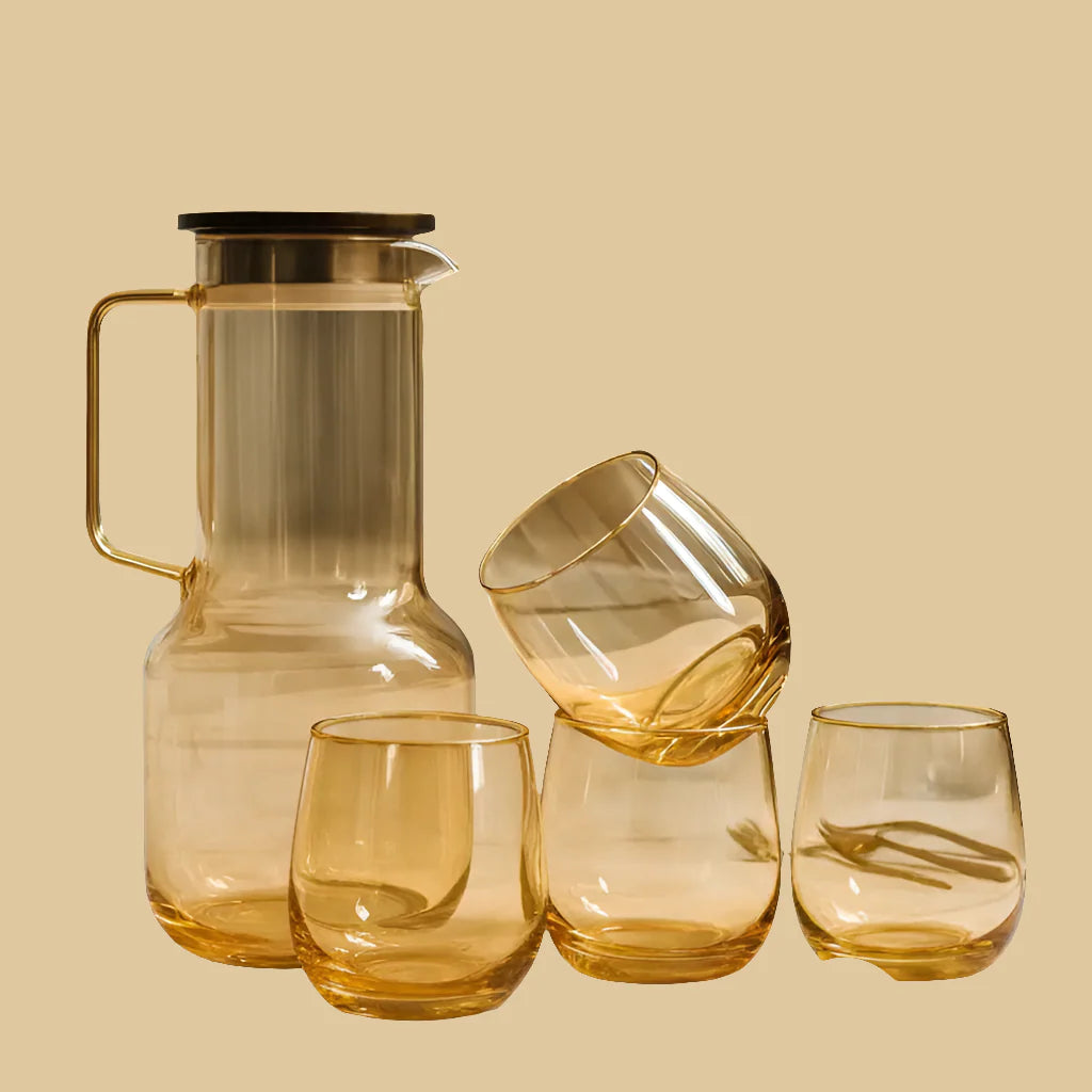 Set of amber glassware including a carafe and three glasses on a beige background