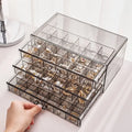 Clear jewelry organizer with multiple compartments filled with earrings on a white surface.