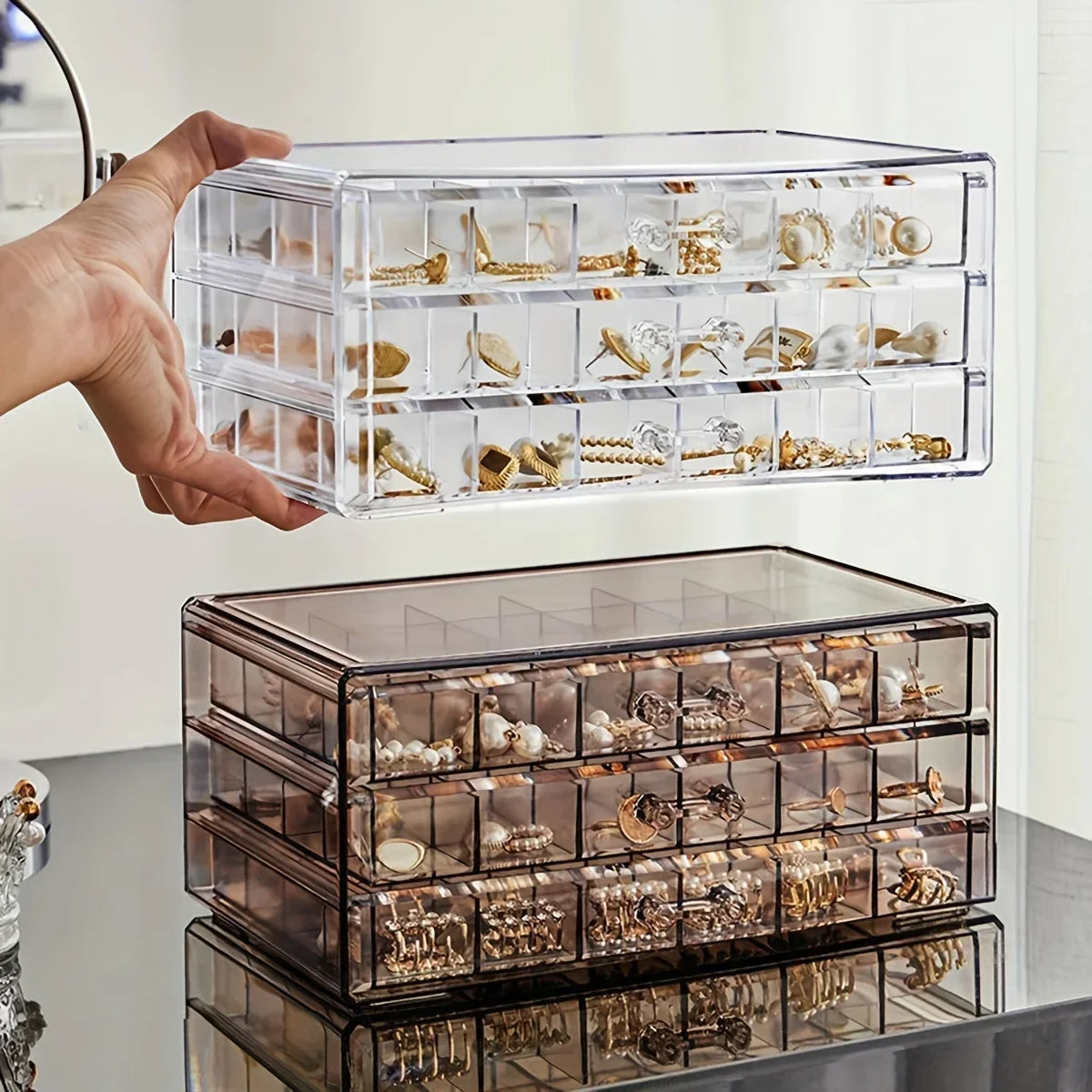 Clear jewelry organizer with various earrings on a reflective surface.