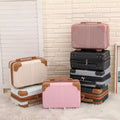 Set of suitcases in various colors stacked against a light-colored wall.