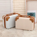 Two white suitcases with brown handles and trim on a light wooden floor.