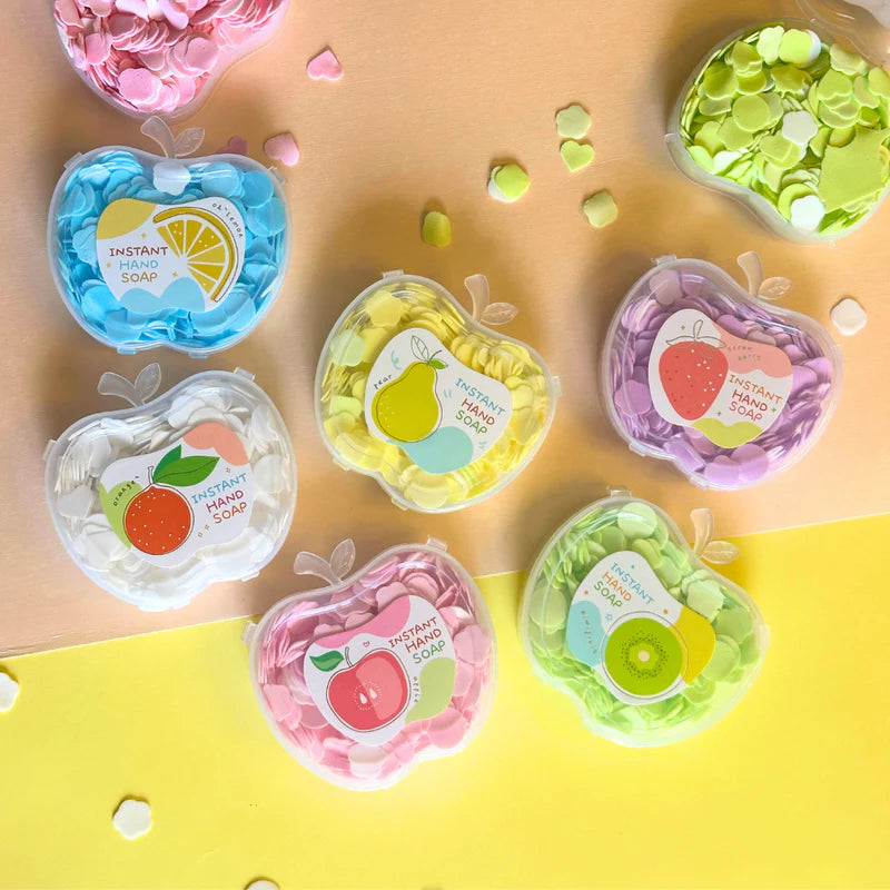 Set of colorful instant hand soaps in heart-shaped containers on a yellow surface.