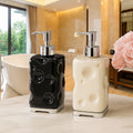 Two decorative soap dispensers, one black and one white, on a bathroom counter with a blurred background.