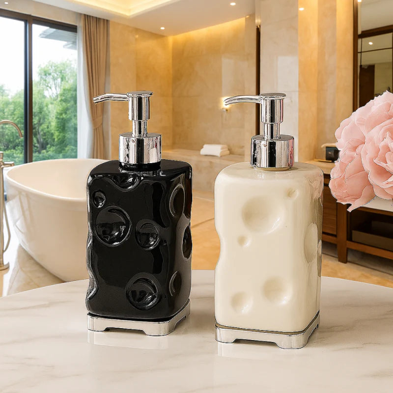 Two decorative soap dispensers, one black and one white, on a bathroom counter with a blurred background.