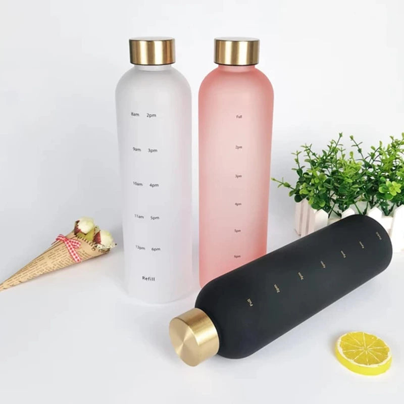 Three water bottles with gold caps on a white surface with decorative items.