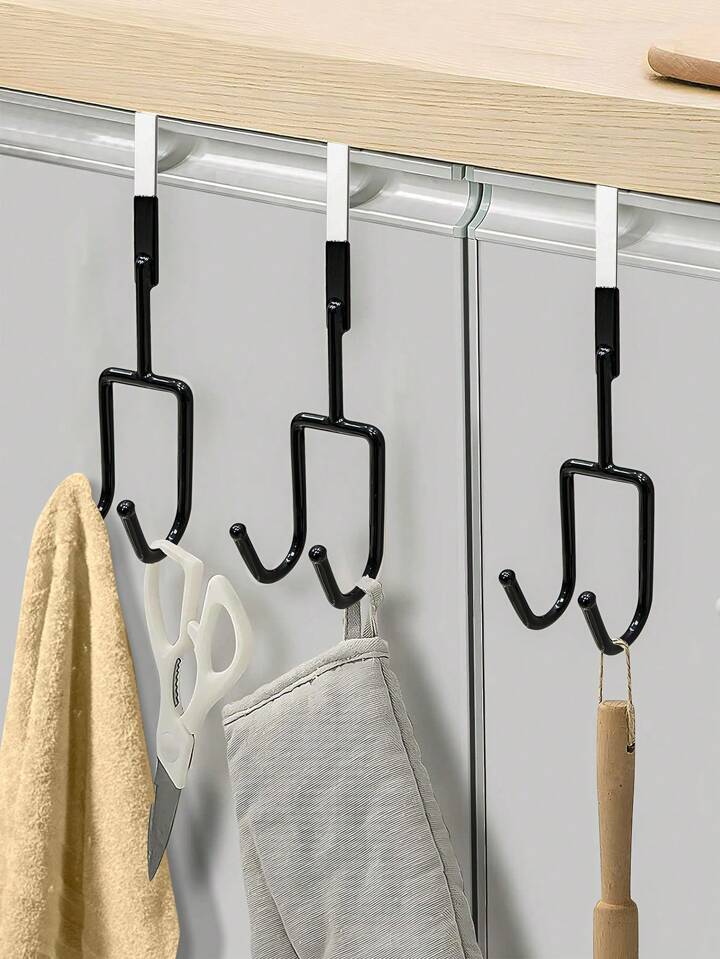 Black hooks on a white door with various items hanging from them.