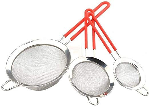 Three metal sifters with red handles on a white surface, one sifting flour.