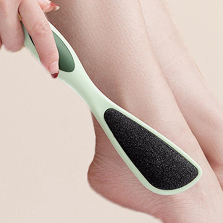 Person using a green and black foot scrubber on their leg.