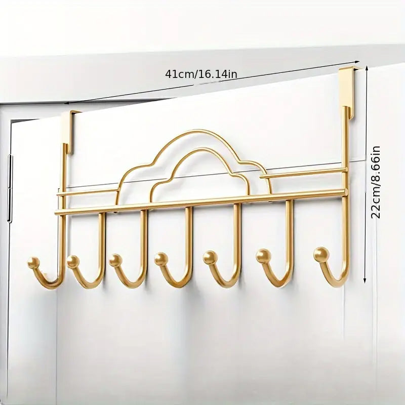 Gold over-the-door hook rack with measurements on a white door background