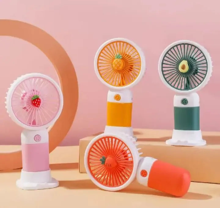 Four portable fans shaped like fruits on a pink and beige background