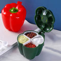 Green pepper-shaped container with compartments filled with spices on a white surface.