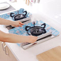 Person placing a portable gas stove on a blue mat with cartoon designs.