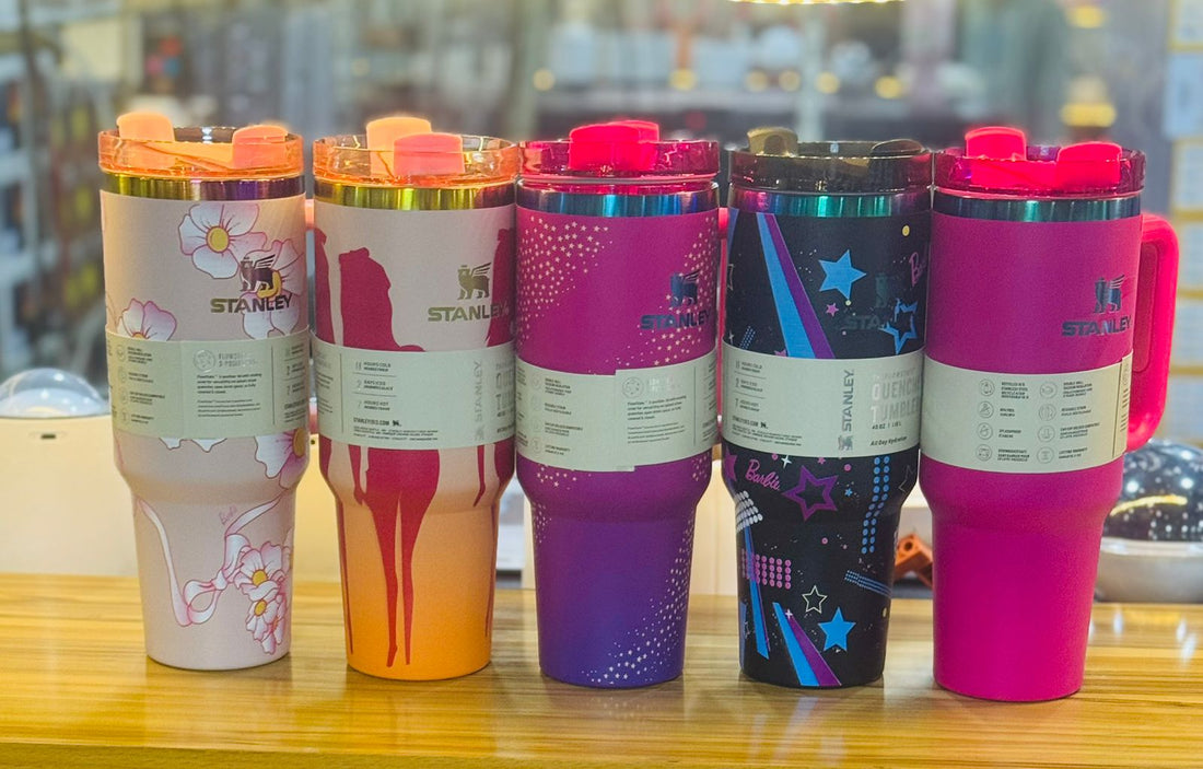 Five colorful tumblers with different designs on a wooden surface.