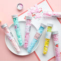 Colorful test tube-shaped containers with decorative labels on a pink background