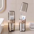 Two transparent toothbrush holders with toothbrushes and toothpaste on a bathroom counter.