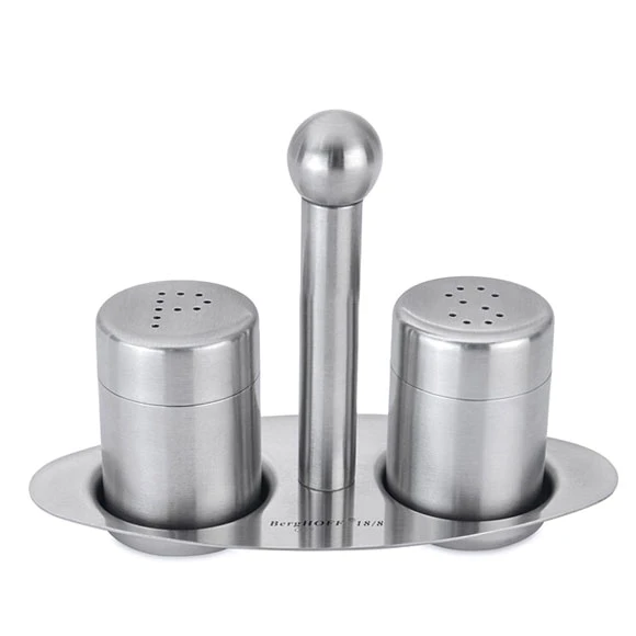 Stainless steel condiment set on a decorative tablecloth with food in the background