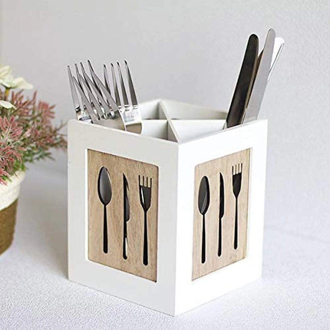 White cube-shaped cutlery holder with silverware on a white background